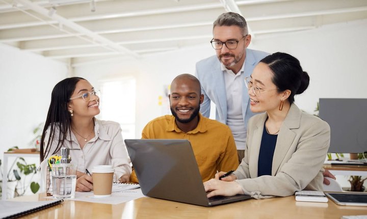Latina woman, black man, white man, and Asian woman exchanging ideas around a laptop