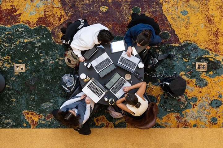 Aerial shot of students studying around a table with their laptops